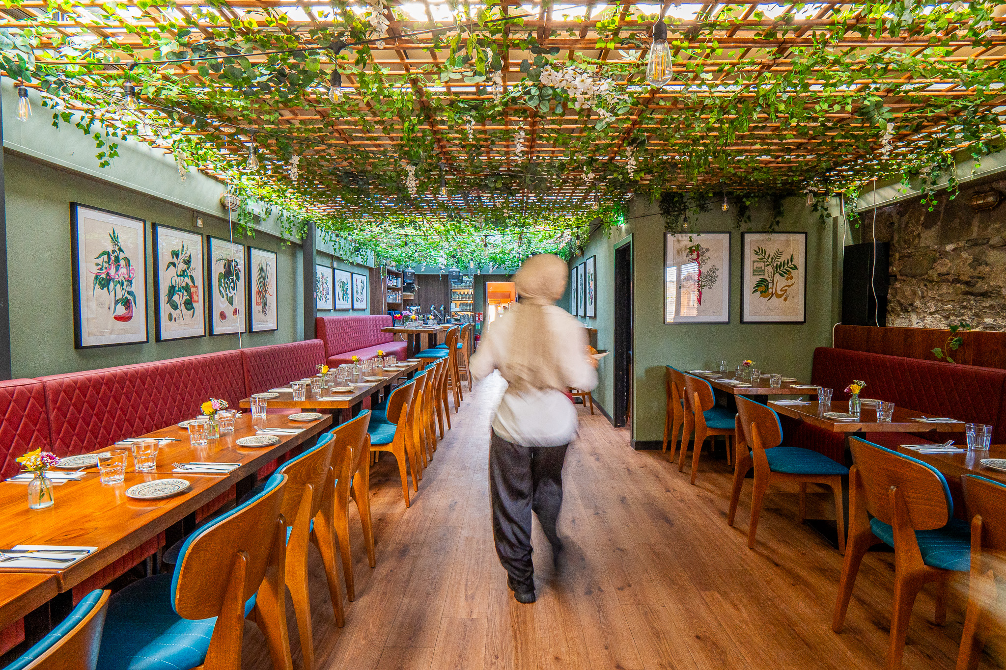 Waiter carrying plates through a Dublin restaurant dining room during service